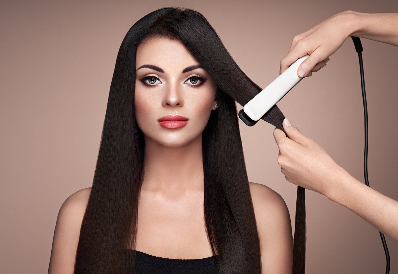 Hairdresser straightening long hair with hair irons